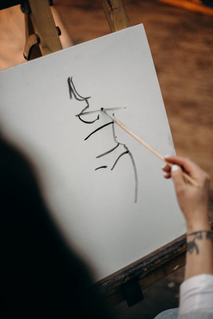 Artist's hand sketching a portrait on canvas with pencil.